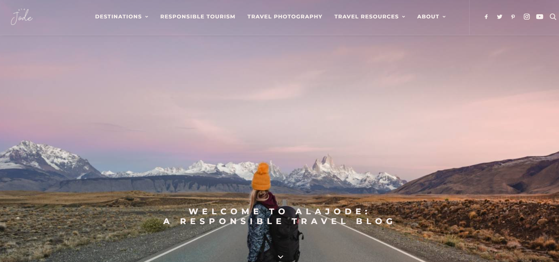 A screenshot of the Alajode travel blog homepage featuring a girl with a backpack standing on the road against a backdrop of mountains.
