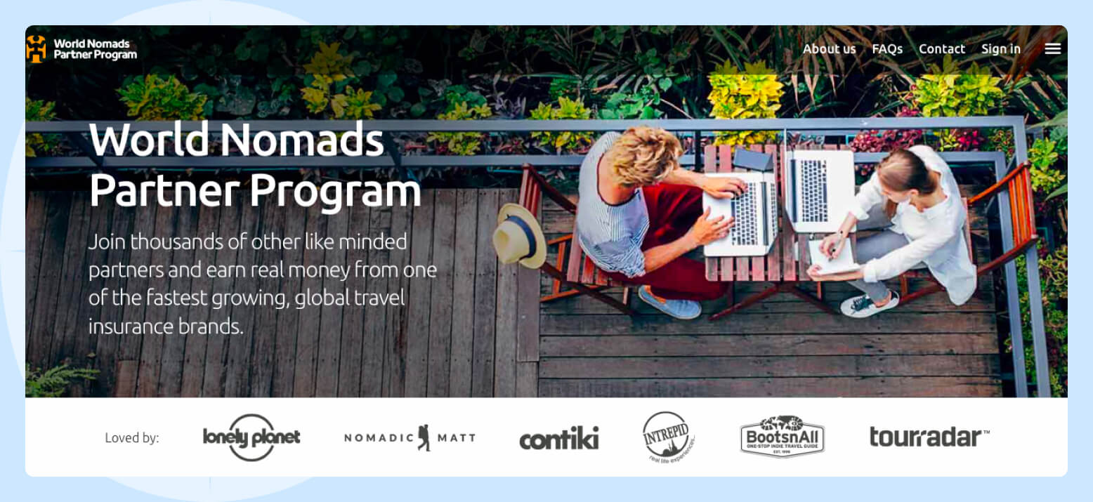 Screenshot of the World Nomads Partner Program featuring a photo of two people sitting and working on their laptop computers on a deck surrounded by palm trees.