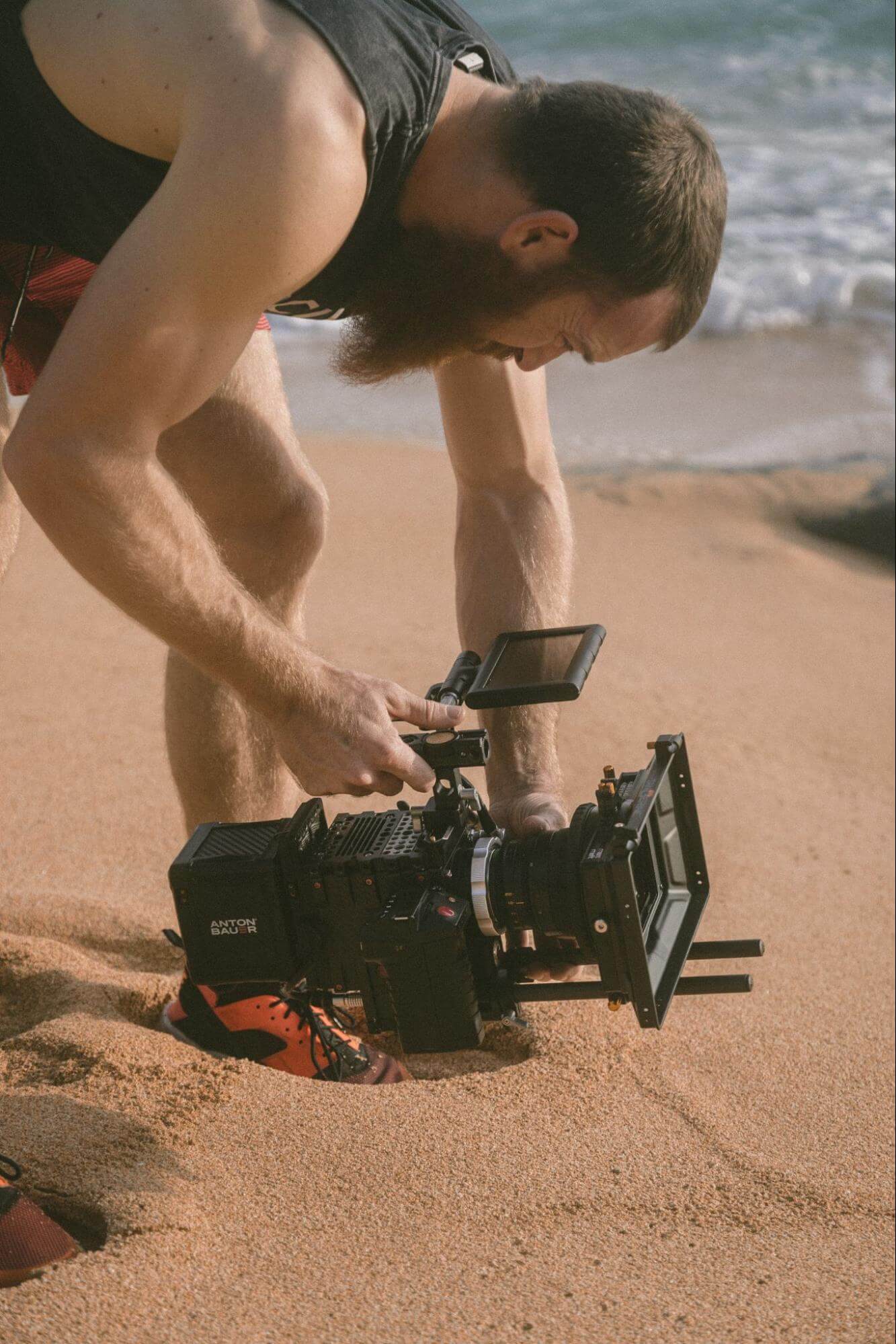 Man checking his camera on a beach after filming