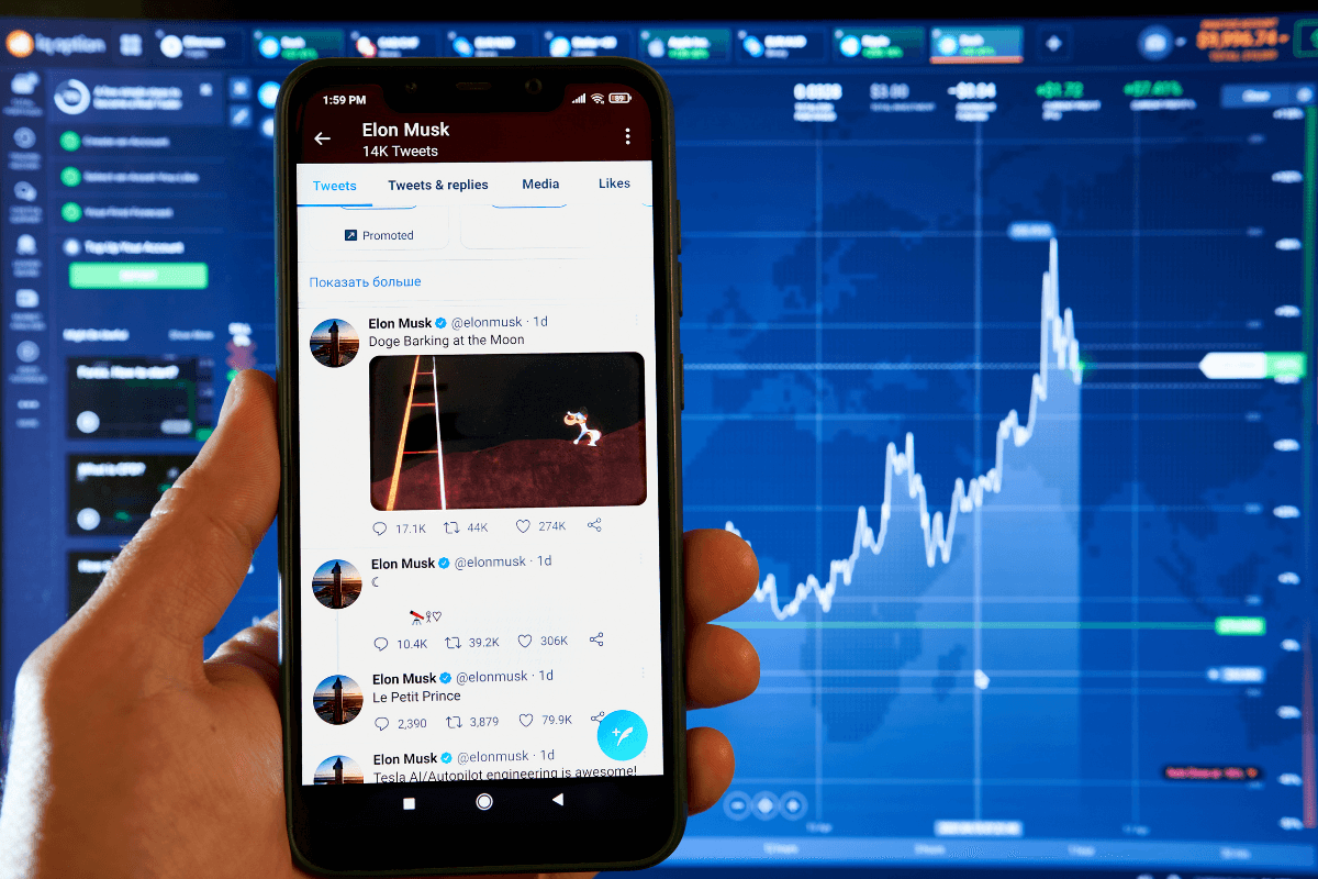 The image shows someone holding a phone and looking at Tweets from Elon Musk. Behind the phone is a web interface displaying analytics, with a bar graph showing growth trajectory.